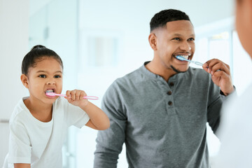 Dads strict about dental. Shot of an adorable little girl and her father brushing their teeth together at home. - Powered by Adobe