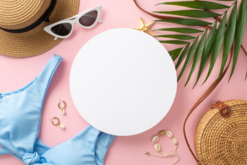 Summer vacation vibes! Top view flat lay of blue swimsuit with sunhat, green palm leaves, earrings, bracelet, sunglasses, bag and flowers on pastel pink background with empty circle for text or advert