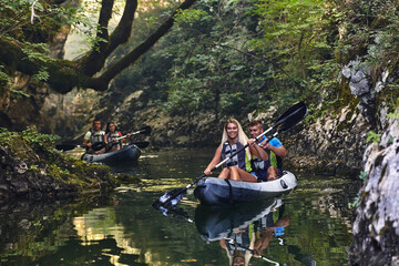 A group of friends enjoying having fun and kayaking while exploring the calm river, surrounding forest and large natural river canyons