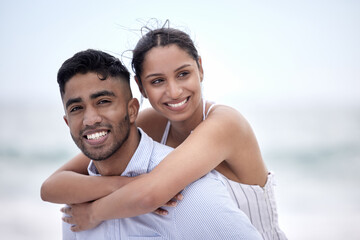 Oh to be young and in love. Cropped portrait of a handsome young man piggybacking his girlfriend along the beach.