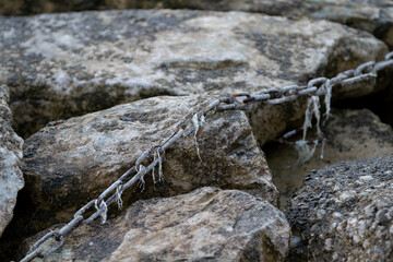 metal chain in which dirt and rubbish hangs is stretched over rocks