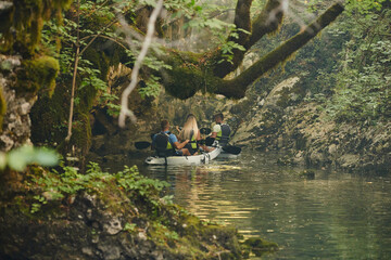 A group of friends enjoying having fun and kayaking while exploring the calm river, surrounding forest and large natural river canyons