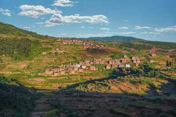 Fototapeta na wymiar Typical Madagascar landscape in region near Alakamisy Ambohimaha, sun setting down over small clay houses, terraced rice fields in foreground and small hills background