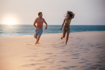 Happy couple running on tropical romantic beach