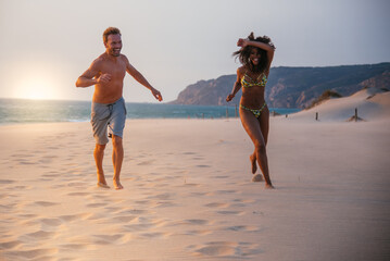 Happy couple running on tropical romantic beach