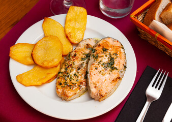 Delicious grilled salmon fillet with garnish of baked potatoes