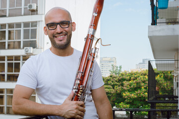 Venezuelan man musician of the symphony orchestra Simon Bolivar, holding a bassoon at home