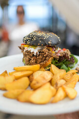 pork burger on squid ink black bun with fries