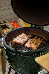 Pork ribs on the grill, green spit and vegetables in the background
