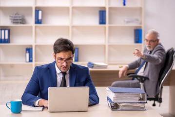 Old male boss and young male employee in the office