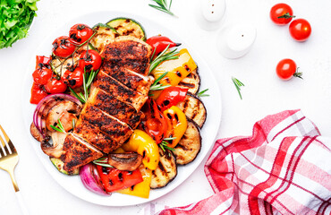 Grilled vegetables and chicken breast fillet. Colorful paprika, zucchini, eggplant, mushrooms, tomatoes, onion and rosemary, served on plate, white table background, top view
