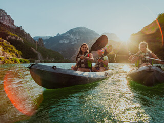A group of friends enjoying fun and kayaking exploring the calm river, surrounding forest and large natural river canyons during an idyllic sunset.