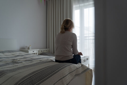 Mature woman sitting alone in the room, sad depressed person. Back view. mental health