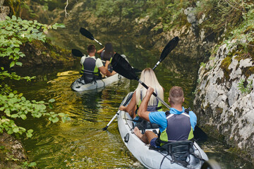 A group of friends enjoying having fun and kayaking while exploring the calm river, surrounding forest and large natural river canyons