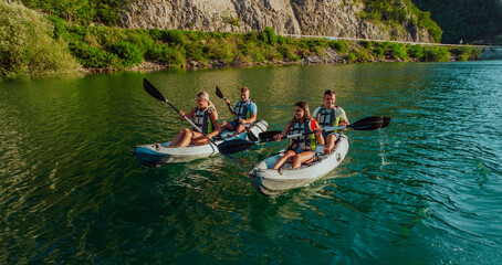 A group of friends enjoying fun and kayaking exploring the calm river, surrounding forest and large natural river canyons during an idyllic sunset. © .shock