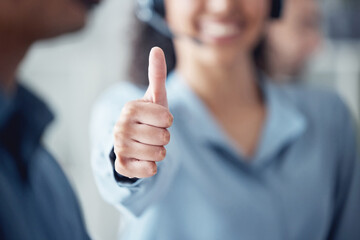 Wrapping up a few calls with success. Closeup shot of an unrecognisable call centre agent showing thumbs up in an office.