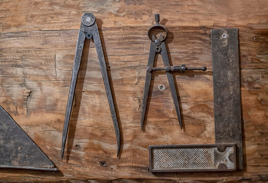 antique tools of carpenter on a wood, antique compass to trace and a square for wood edging, old drawing equipment, horizontal - Powered by Adobe