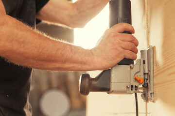 Arms and hands of craftsman with tool cutting wood