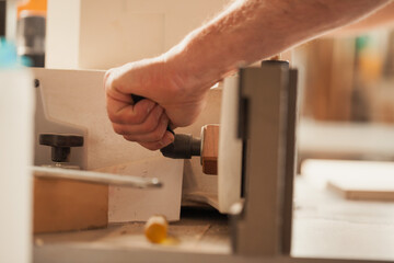 The carpenter's hand grips a self-made vise using a lever