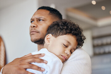 Mixed race boy sleeping on his dads shoulder. Boy feeling safe in fathers arms. Father holding his tired son