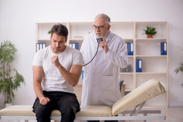 Fototapeta premium Young male patient visiting old male doctor