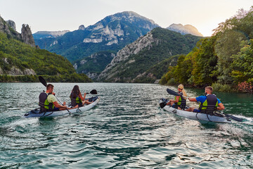 A group of friends enjoying fun and kayaking exploring the calm river, surrounding forest and large natural river canyons during an idyllic sunset.