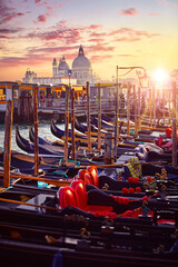 Venice, Italy. Gondolas floqting by the docks of Grand Canal in Venezia. Sunset view Cathedral Santa Maria della Salute venice. Picturesque panoramic skyline landscape - 596492496