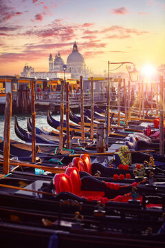Venice, Italy. Gondolas floqting by the docks of Grand Canal in Venezia. Sunset view Cathedral Santa Maria della Salute venice. Picturesque panoramic skyline landscape