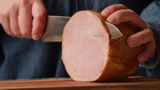 Woman slices ham bacon meat thick pieces on a wooden board, beef or pork jamon. Chef cooking breakfast, smoked bacon in cafe. 