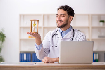 Young male doctor in time management concept