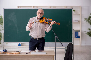 Old male teacher playing violin in the classroom © Elnur