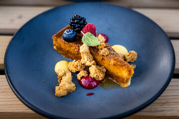 Close-up of Three Milks Cake with Caramel, Piloncillo Crowns, and Berries on Rustic Wooden Table
