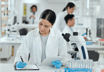 Shes in the zone. Shot of a young woman making notes in her lab.