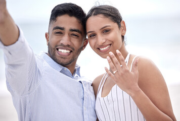 Were getting married. Cropped portrait of a young, newly betrothed couple showing off their engagement on the beach.