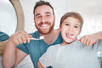 Were on top of our oral hygiene. Shot of a little boy and his father brushing their teeth together at home.
