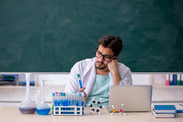 Young male chemist in front of blackboard