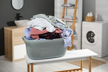 Laundry basket filled with clothes on table in bathroom