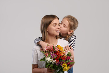 Fototapeta na wymiar Little daughter congratulating her mom with flowers on white background. Happy Mother's Day