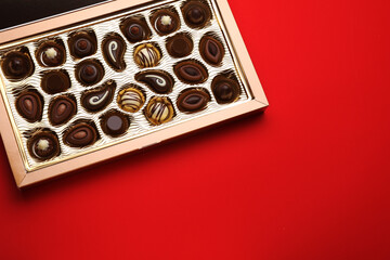 Box of delicious chocolate candies on red background, top view. Space for text