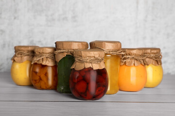 Jars with canned fruit jams on wooden table
