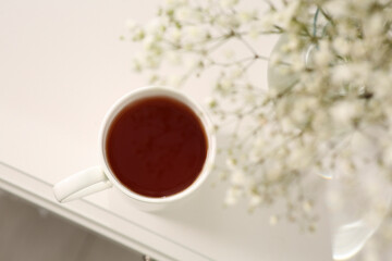 Ceramic mug with tea on white bedside table indoors, top view