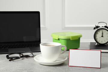 Cup of coffee, glasses, laptop and blank card on light gray table. Business lunch concept