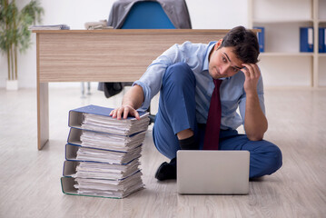 Obraz premium Young male employee unhappy with excessive work in the office