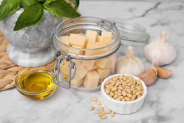 Different ingredients for cooking tasty pesto sauce on white marble table, closeup
