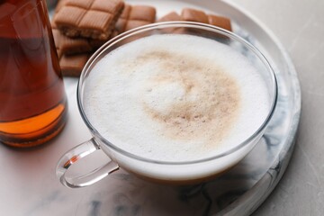 Bottle of delicious syrup, glass of coffee and caramel candies on grey table, closeup