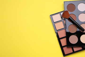 Different contouring palettes and brush on yellow background, flat lay with space for text....
