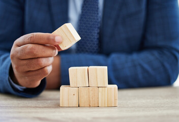 By failing to prepare, you are preparing to fail. Shot of an unrecognisable businessman working with wooden building blocks in a modern office.