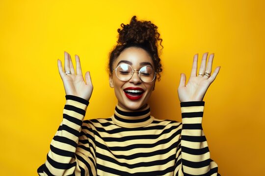 Happy young mixed race woman rising her hands over yellow studio background. Generative AI