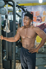 Fototapeta na wymiar A young black male exercises in a gym, building physical strength and vitality through weight training for sports performance.