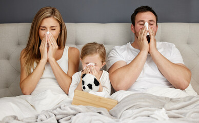 Family isolation session. Shot of a family blowing their noses while sick at home.
